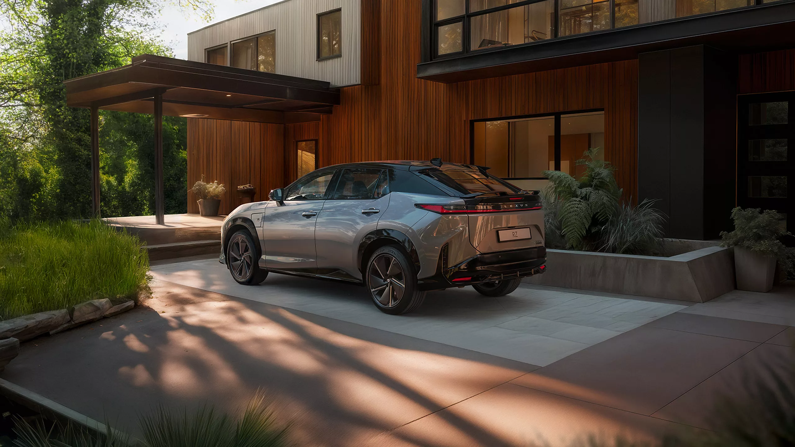 Lexus RZ vu de l'arri&egrave;re devant une maison &mdash; hayon mains libres